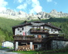 In primo piano il rifugio e sullo sfondo la catena del Tredenus che abbraccia la conca del Volano